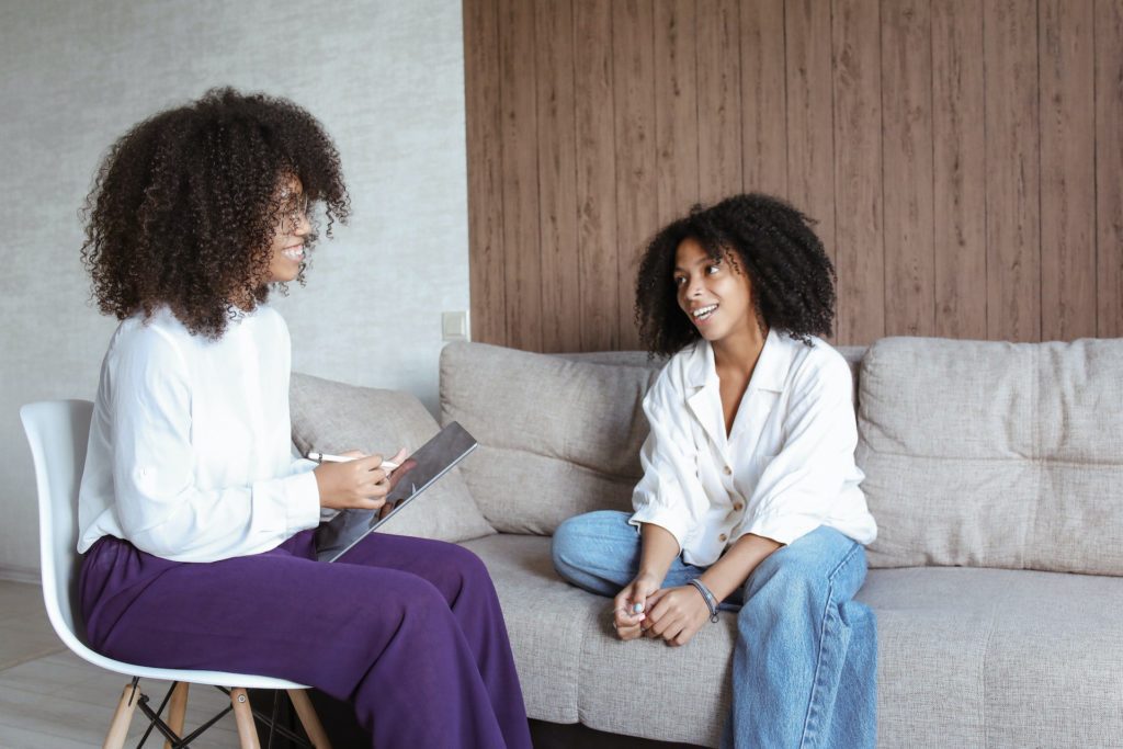 counselor with clipboard talking to patient sitting on couch
