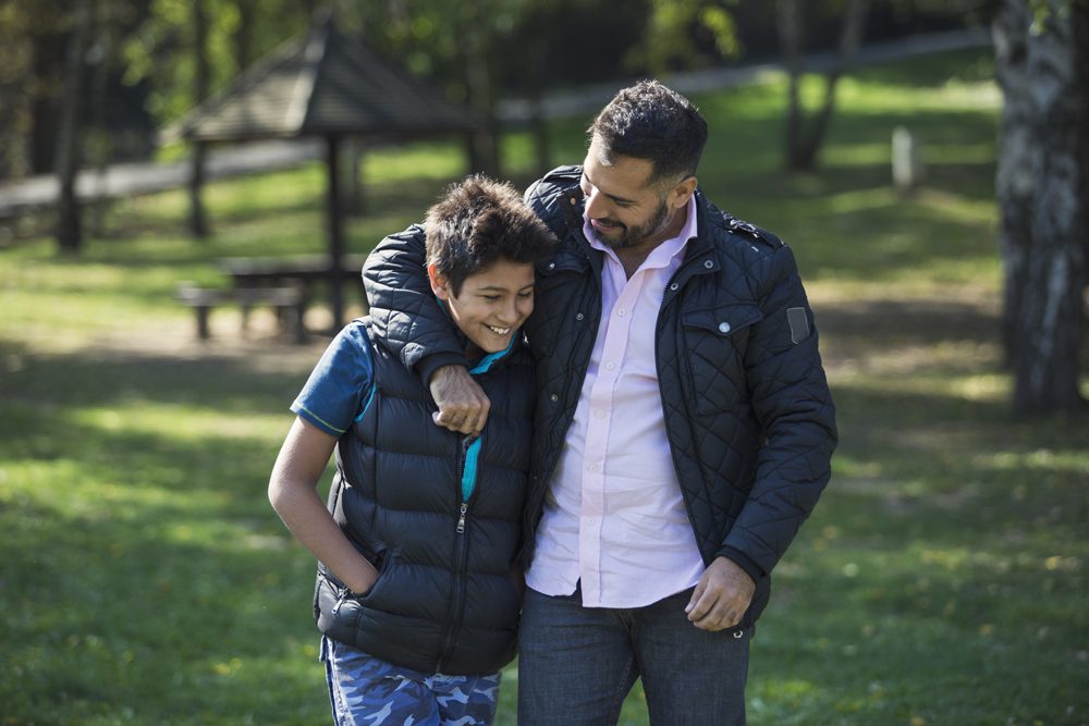 father walking with his son through a park on a nice day