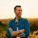 man standing outdoors smiling at sunset