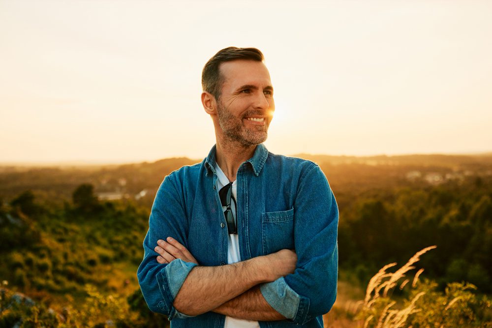 man standing outdoors smiling at sunset