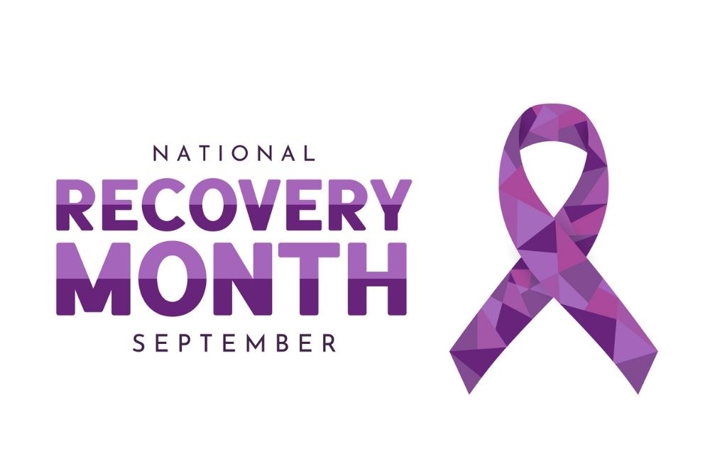 Purple geometric ribbon symbol with the words “National Recovery Month September,” representing awareness for recovery and mental health.